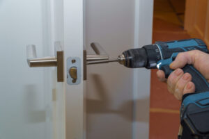 House entrance rear view of a good looking man working as handyman and fixing a door lock